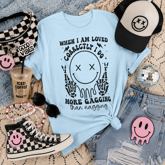 Graphic T-Shirt — "When I Am Loved Correctly I Do More Gagging Than Nagging" Smiley Skeleton Tee
