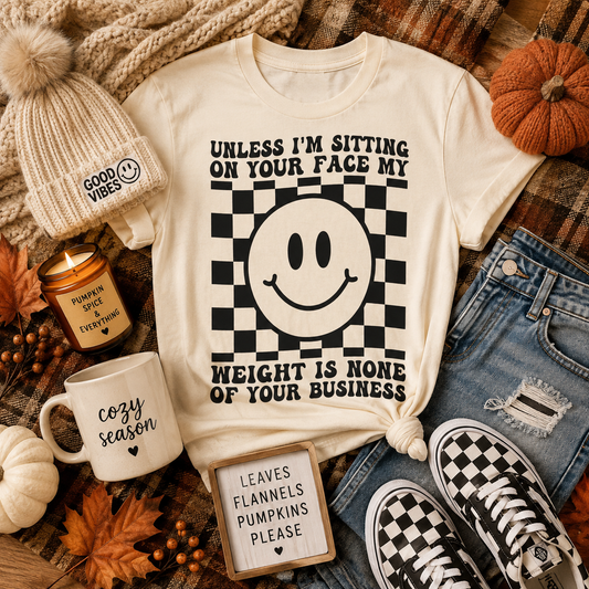 Graphic T-Shirt — "Unless I’m Sitting On Your Face My Weight Is None Of Your Business" Smiley Checker Tee